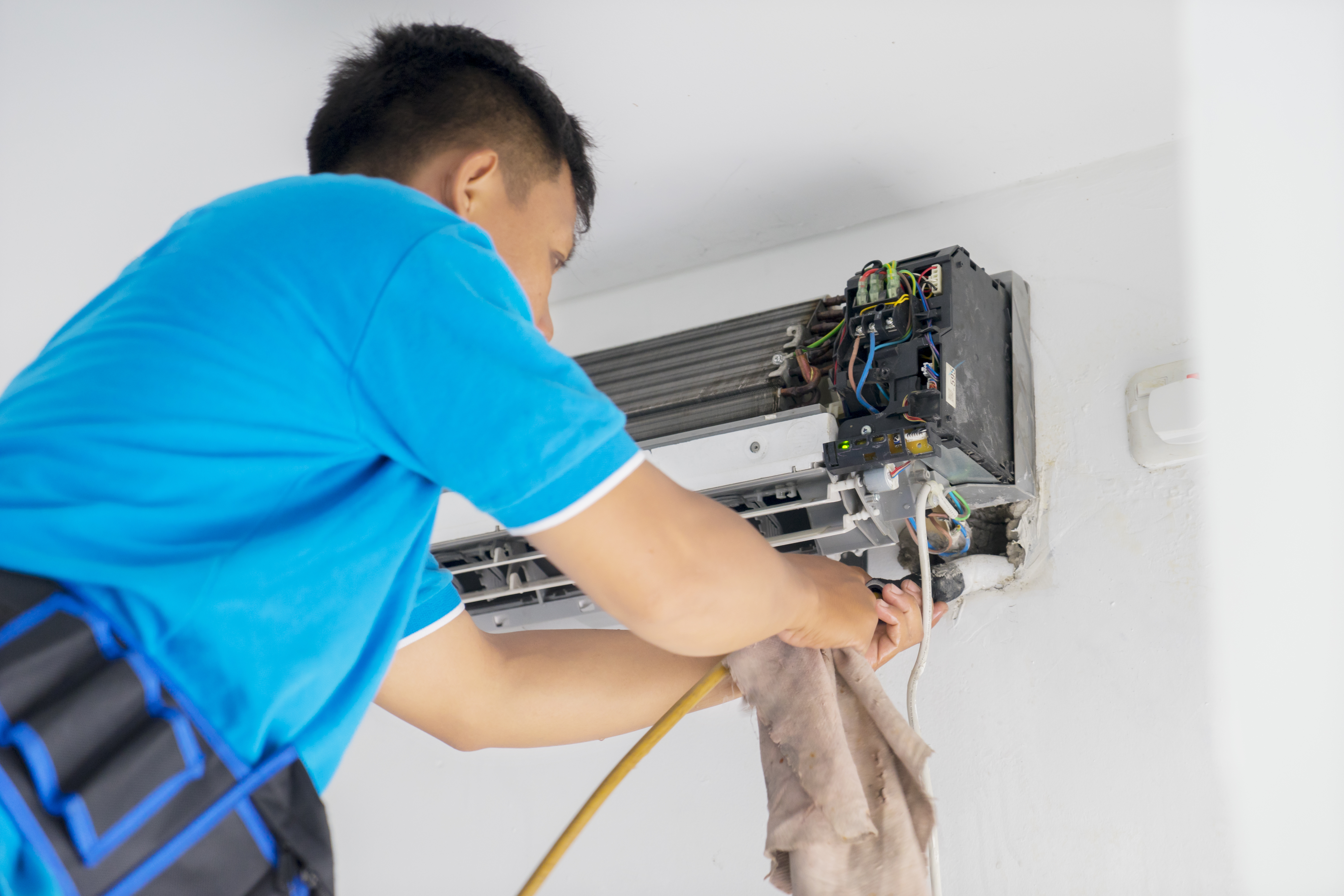 Male technician cleans coil cooler of air conditioner